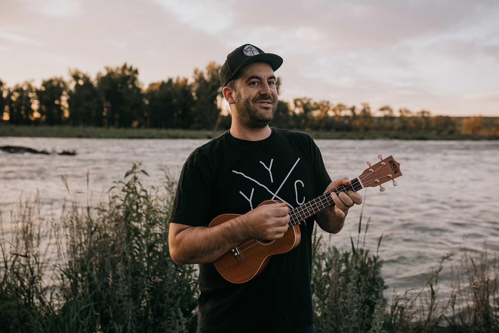 Dave Simpson playing a Honolua Ukulele by the river at sunset